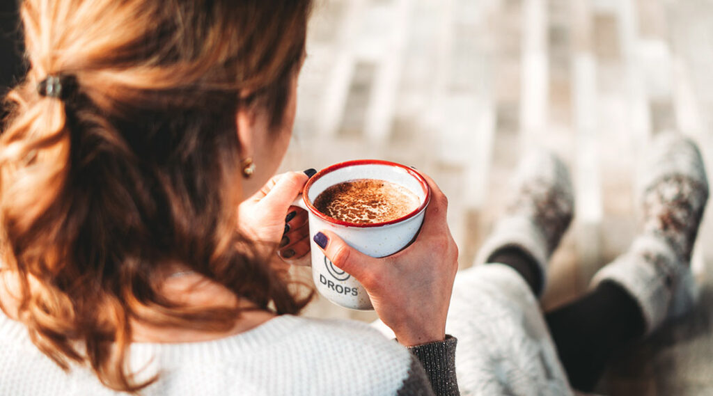 mulher a beber chocolate quente em caneca publicitária